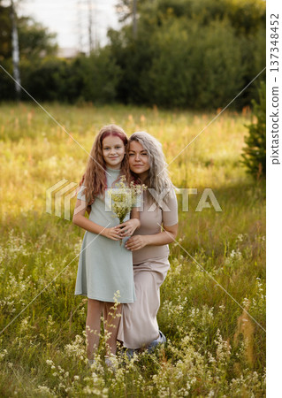 Radiant Outdoor Scene Showing Maternal Love With Wildflowers And Joyful Expressions Radiant Outdoor Scene Showing Maternal Love With Wildflowers And Joyful Expressions 137348452