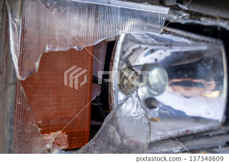 A car headlight is broken with a damaged lens and exposed wires, located in a parking area on a cloudy day needing repairs A car headlight is broken with a damaged lens and exposed wires, located in a parking area on a cloudy day needing repairs 137348609