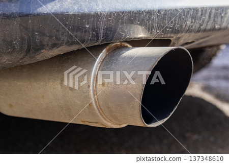 Close up of a car exhaust pipe with dirt buildup and shiny metal parts under clear sunlight on a roadway Close up of a car exhaust pipe with dirt buildup and shiny metal parts under clear sunlight on a roadway 137348610