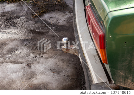 A green car shows a towbar at the back while parked on icy ground in a rural area during winter 137348615