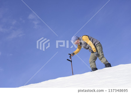 An elderly man living in a snowy rural area is using a walking stick for rehabilitation 137348695