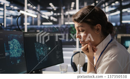 Software developer monitors server clusters performing AI training and inference tasks. IT expert supervising high tech computing systems managing machine learning storage operations, camera A closeup Software developer monitors server clusters performing AI training and inference tasks. IT expert supervising high tech computing systems managing machine learning storage operations, camera A closeup 137350538
