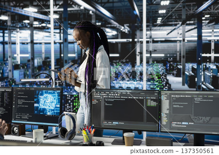 Programmer coding in data center, updating machine learning automation scripts. African american woman in server hub programming artificial intelligence algorithms, debugging equipment racks Programmer coding in data center, updating machine learning automation scripts. African american woman in server hub programming artificial intelligence algorithms, debugging equipment racks 137350561