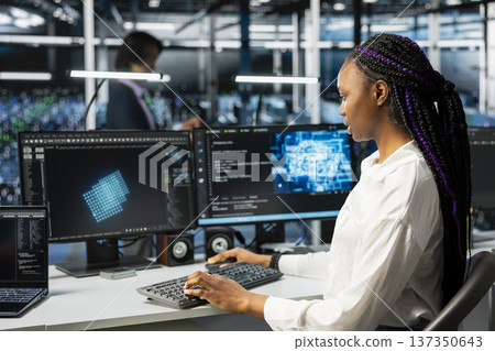 Computer scientist in high tech data center managing AI training datasets. African american woman oversees machine learning in server room supporting scalable infrastructure for AI apps Computer scientist in high tech data center managing AI training datasets. African american woman oversees machine learning in server room supporting scalable infrastructure for AI apps 137350643