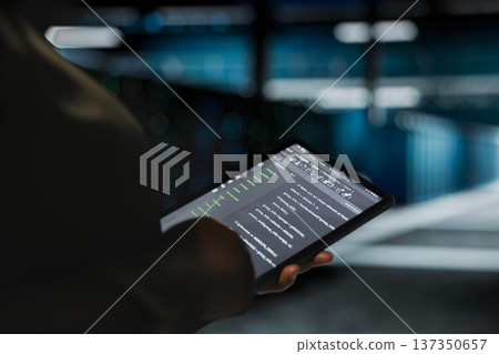 Data center computer scientist using tablet to optimize network infrastructure, planning capacity. Employee managing server room resources with device for improved reliability and uptime 137350657