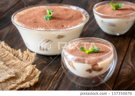 Three classic Italian tiramisu desserts served in elegant glass bowls with cocoa powder Three classic Italian tiramisu desserts served in elegant glass bowls with cocoa powder 137350870