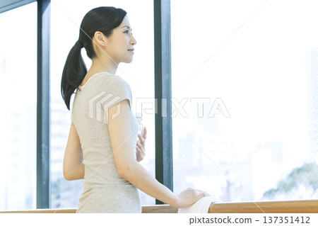 A woman standing by the window holding a plastic bottle A woman standing by the window holding a plastic bottle 137351412