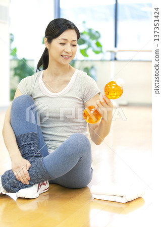 Woman sitting on the floor and holding dumbbells Woman sitting on the floor and holding dumbbells 137351424