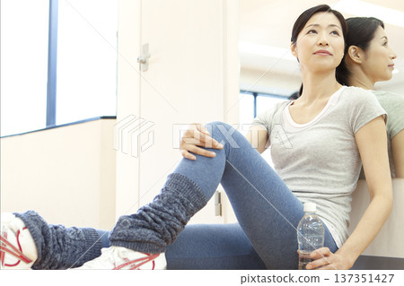 一名女子坐在健身房的地板上。 137351427