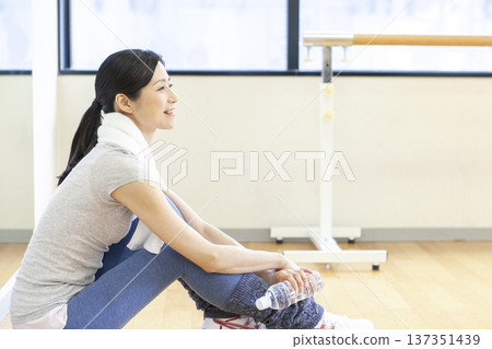 Woman sitting on the floor in a fitness gym Woman sitting on the floor in a fitness gym 137351439