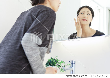 Middle-aged woman looking in the mirror Middle-aged woman looking in the mirror 137351457