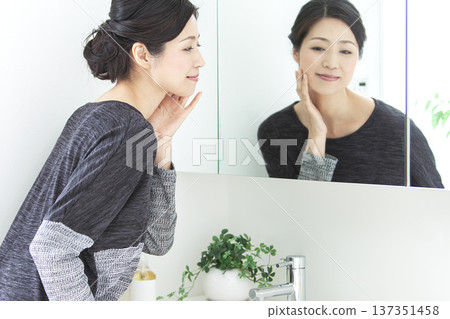Middle-aged woman looking in the mirror Middle-aged woman looking in the mirror 137351458