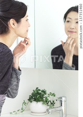 Middle-aged woman looking in the mirror 137351460