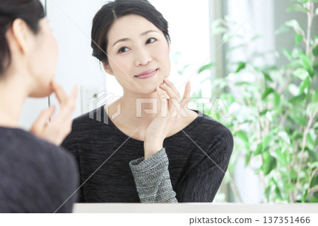 Middle-aged woman looking in the mirror Middle-aged woman looking in the mirror 137351466