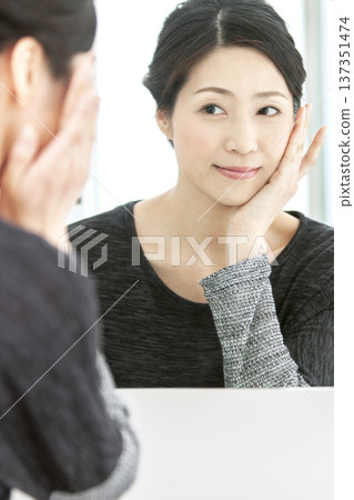 Middle-aged woman looking in the mirror Middle-aged woman looking in the mirror 137351474