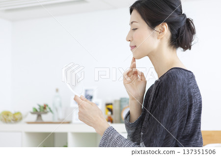 A woman watching a hand mirror 137351506