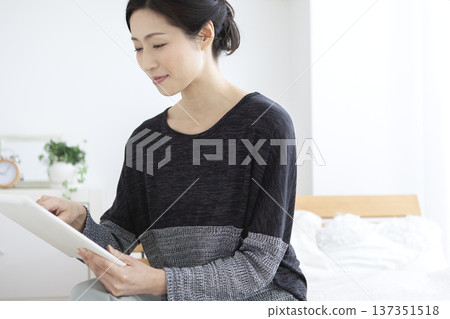 Middle-aged woman operating a tablet PC Middle-aged woman operating a tablet PC 137351518