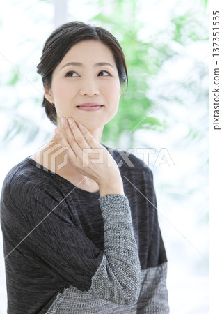 Middle-aged woman with hands on face Middle-aged woman with hands on face 137351535
