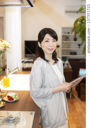 一位中年婦女拿著一台平板電腦 137351725