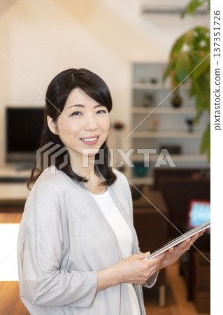 一位中年婦女拿著一台平板電腦 137351726