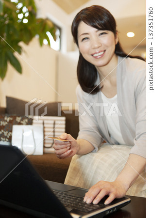 Middle-aged woman holding a credit card Middle-aged woman holding a credit card 137351760