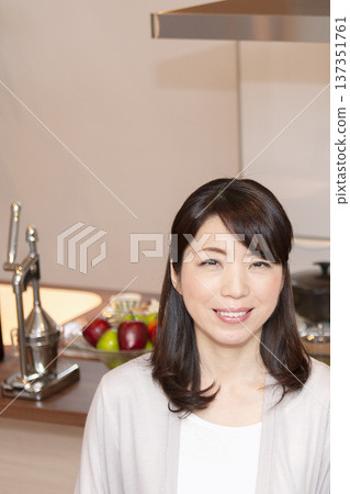 Middle-aged woman standing in the kitchen Middle-aged woman standing in the kitchen 137351761