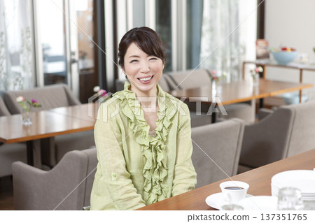 A middle-aged woman sitting at a counter in a cafe A middle-aged woman sitting at a counter in a cafe 137351765