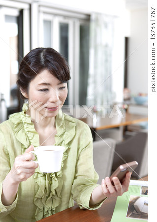 A middle-aged woman sitting at a counter in a cafe 137351767