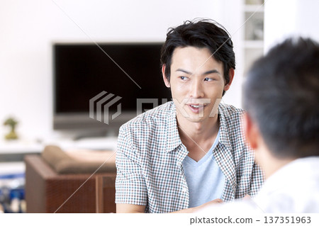 Father and son talking in the living room 137351963