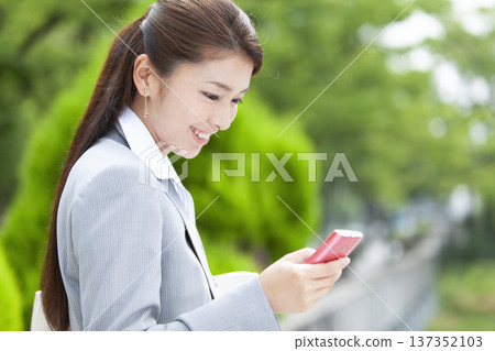 Business woman operating a smartphone 137352103