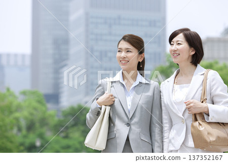 Two businesswomen walking in an office district Two businesswomen walking in an office district 137352167