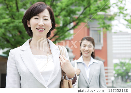Two businesswomen walking in an office district Two businesswomen walking in an office district 137352188