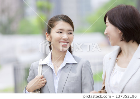 Two businesswomen walking in an office district Two businesswomen walking in an office district 137352196