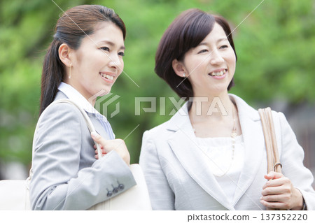 Two businesswomen walking in an office district Two businesswomen walking in an office district 137352220