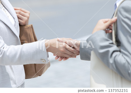 Two businesswomen shaking hands in an office district 137352231