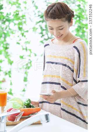 一位女士在廚房操作智慧型手機 137352246