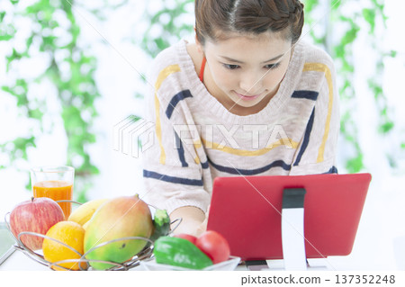 A woman who manipulates a tablet in the kitchen 137352248