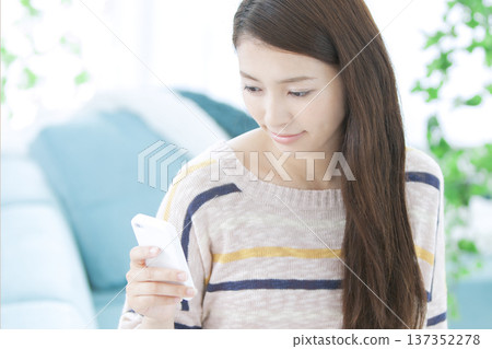 一個女人在沙發上操作智能手機 137352278