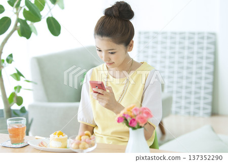 一名女子在桌旁操作智慧型手機。 137352290