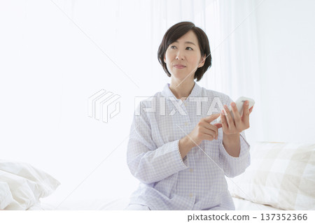 Woman operating a smartphone in bed Woman operating a smartphone in bed 137352366