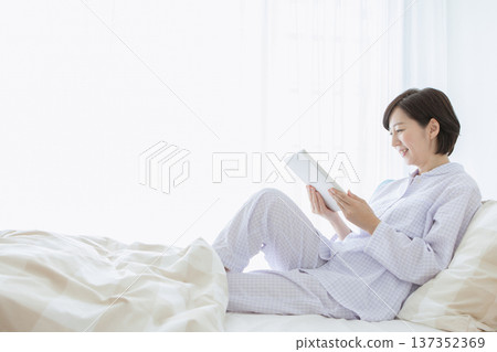 A woman who manipulates a tablet in bed 137352369