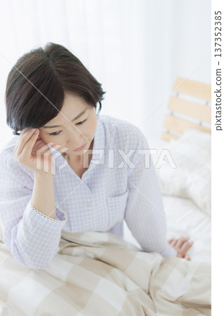 Middle-aged woman sitting in bed Middle-aged woman sitting in bed 137352385