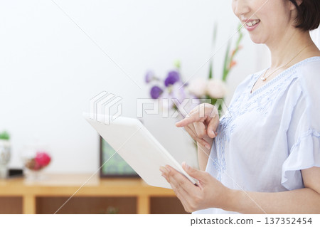 一位中年婦女正在操作平板電腦 137352454