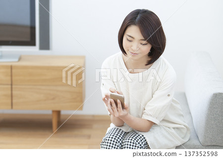 在客廳裡操作智能手機的女人 137352598