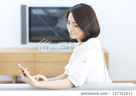 A woman who operates a smartphone in the living room 137352611