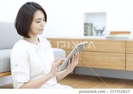 女人在客廳裡操作平板電腦 137352627