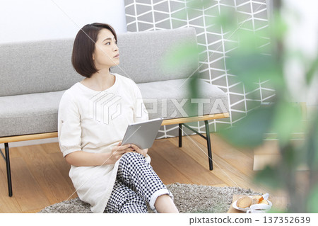 Woman operating a tablet in the living room Woman operating a tablet in the living room 137352639