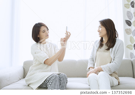Mother and daughter operating smartphones Mother and daughter operating smartphones 137352698