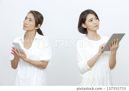 Mother and daughter operating a tablet and smartphone Mother and daughter operating a tablet and smartphone 137352733
