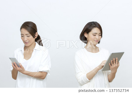 Mother and daughter operating a tablet and smartphone Mother and daughter operating a tablet and smartphone 137352734